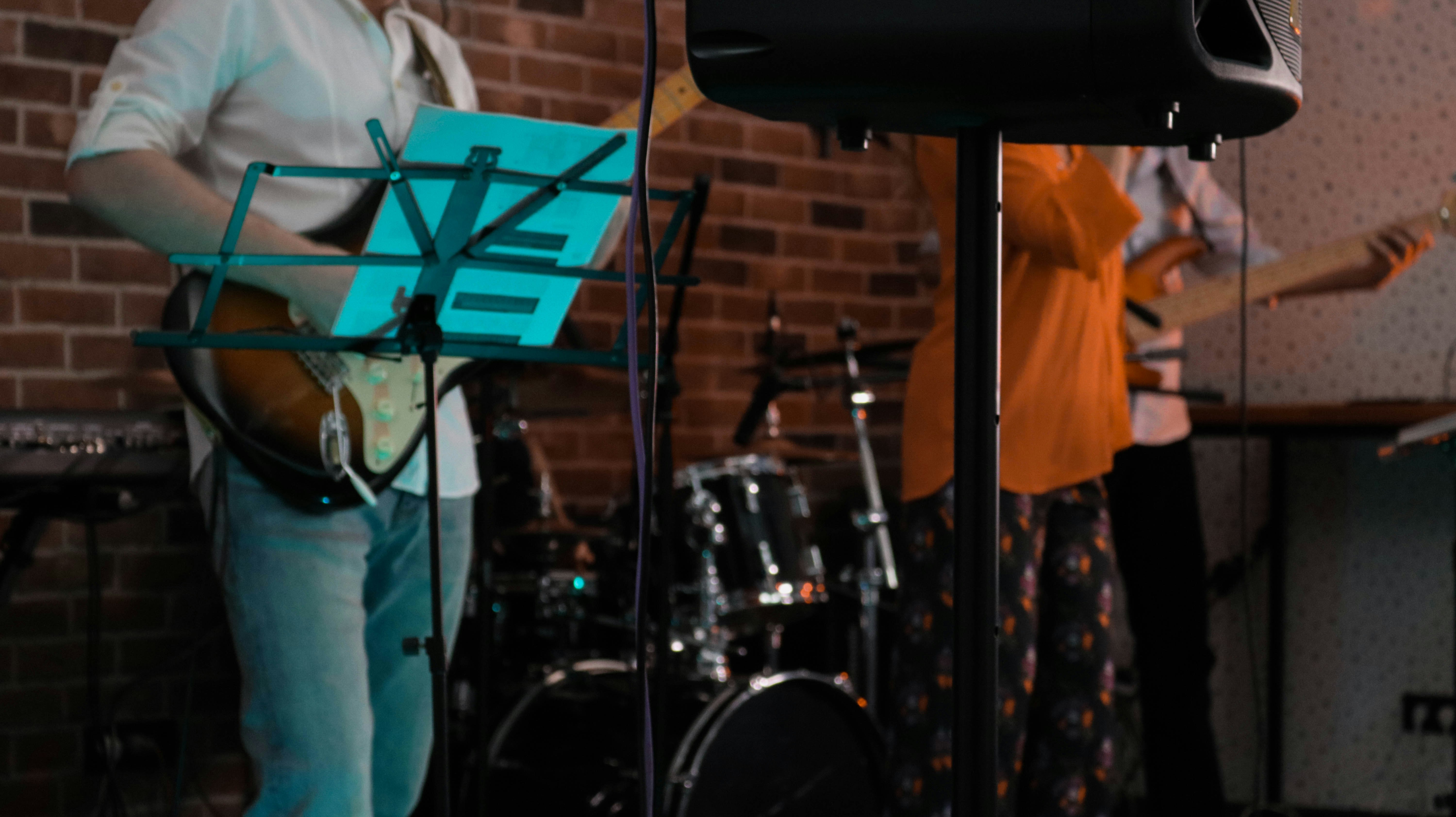 man in white shirt standing near black drum set